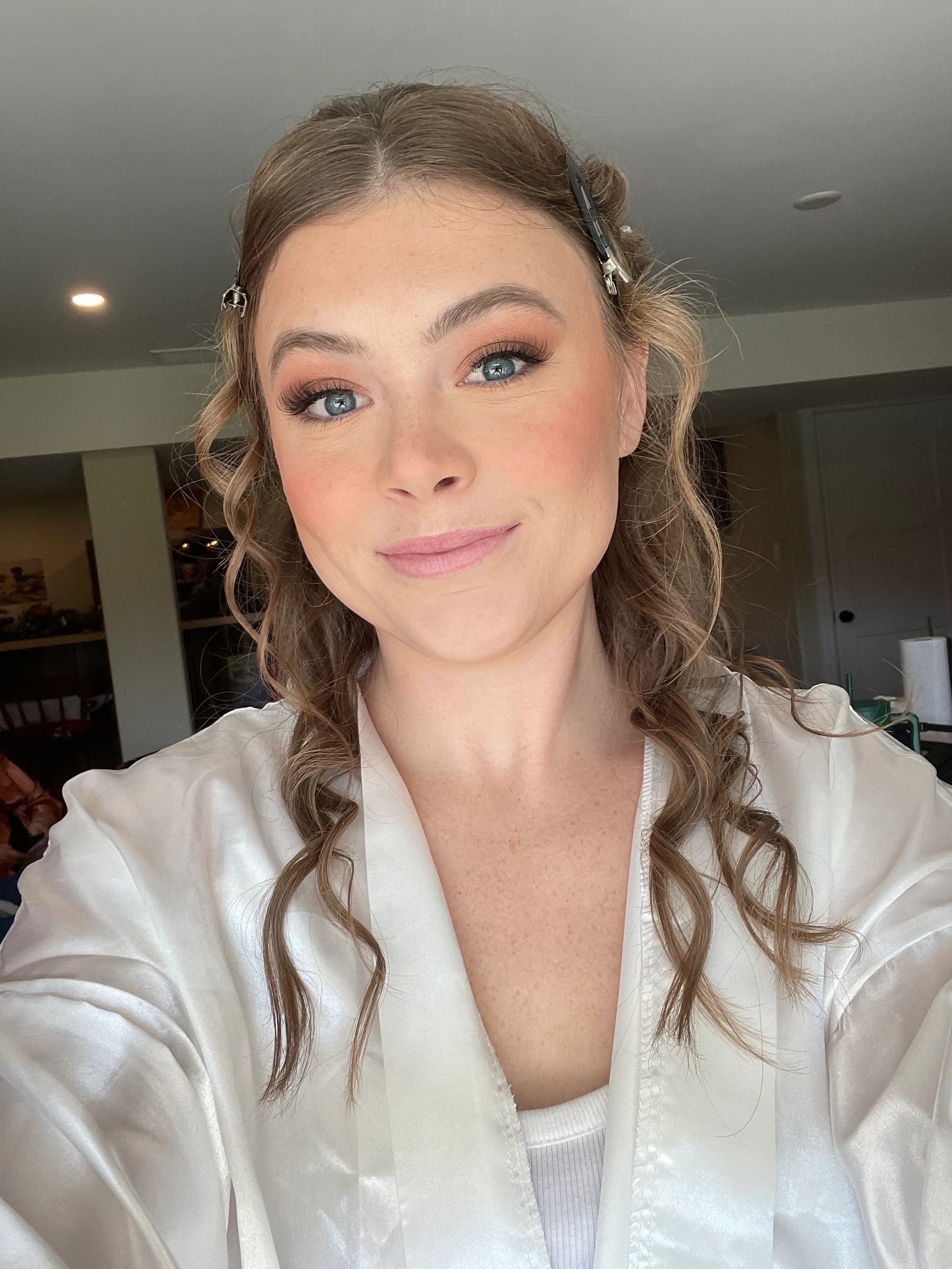 A finished makeup look with softly defined eyes and pink lips, worn with a white robe.