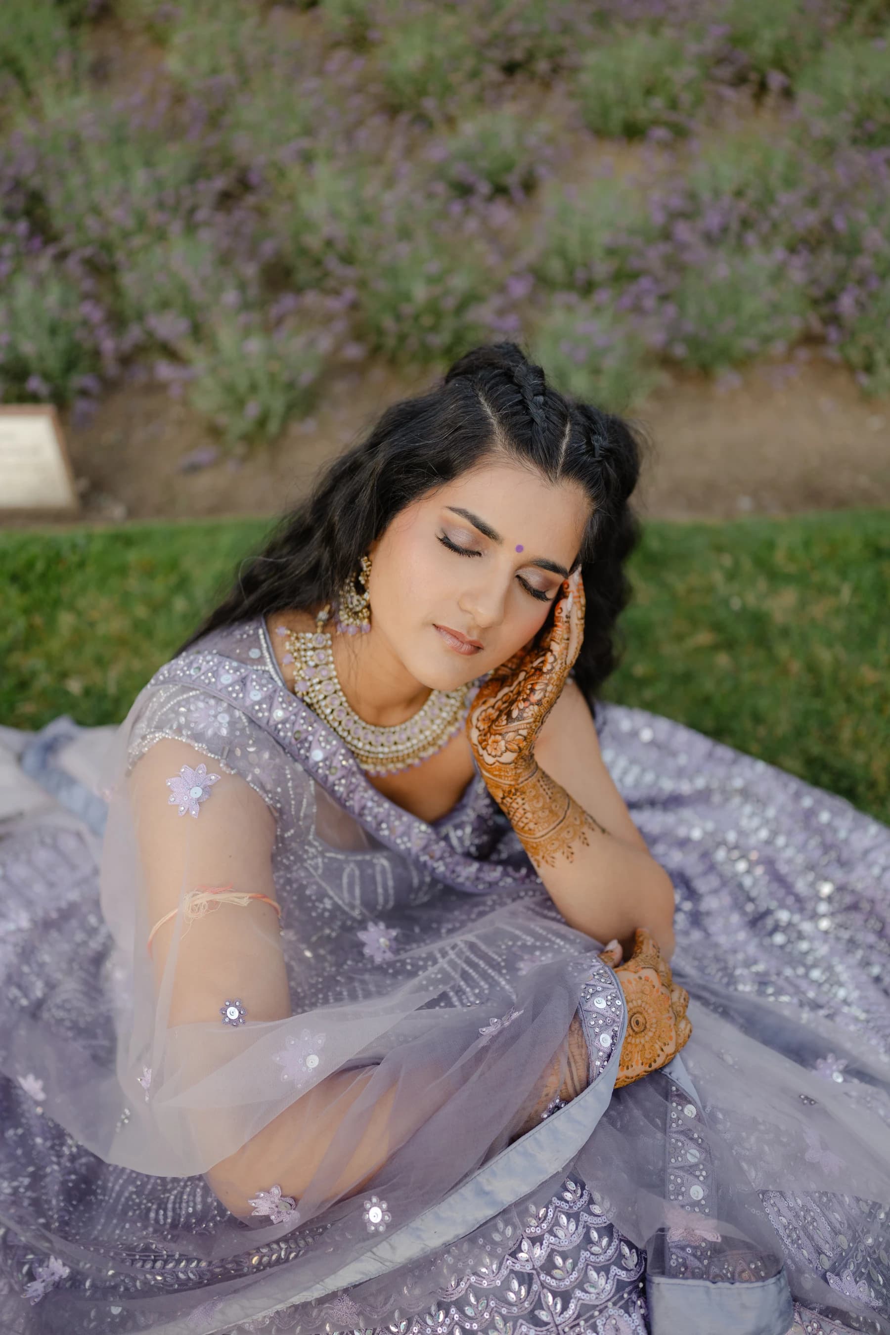 A makeup look with defined eyes and a soft lip, paired with a lavender outfit and gold jewellery.