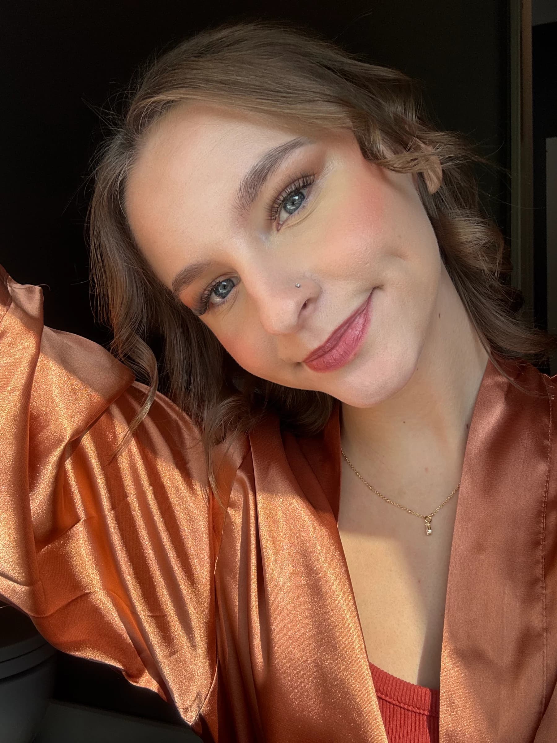 A close-up makeup look with rosy cheeks and pink lips in warm sunlight.